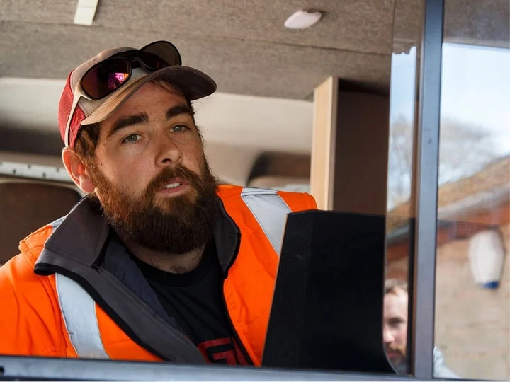 A man with a beard and glasses looking out the window