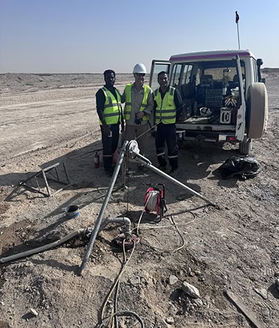 Three men standing in the desert near a truck